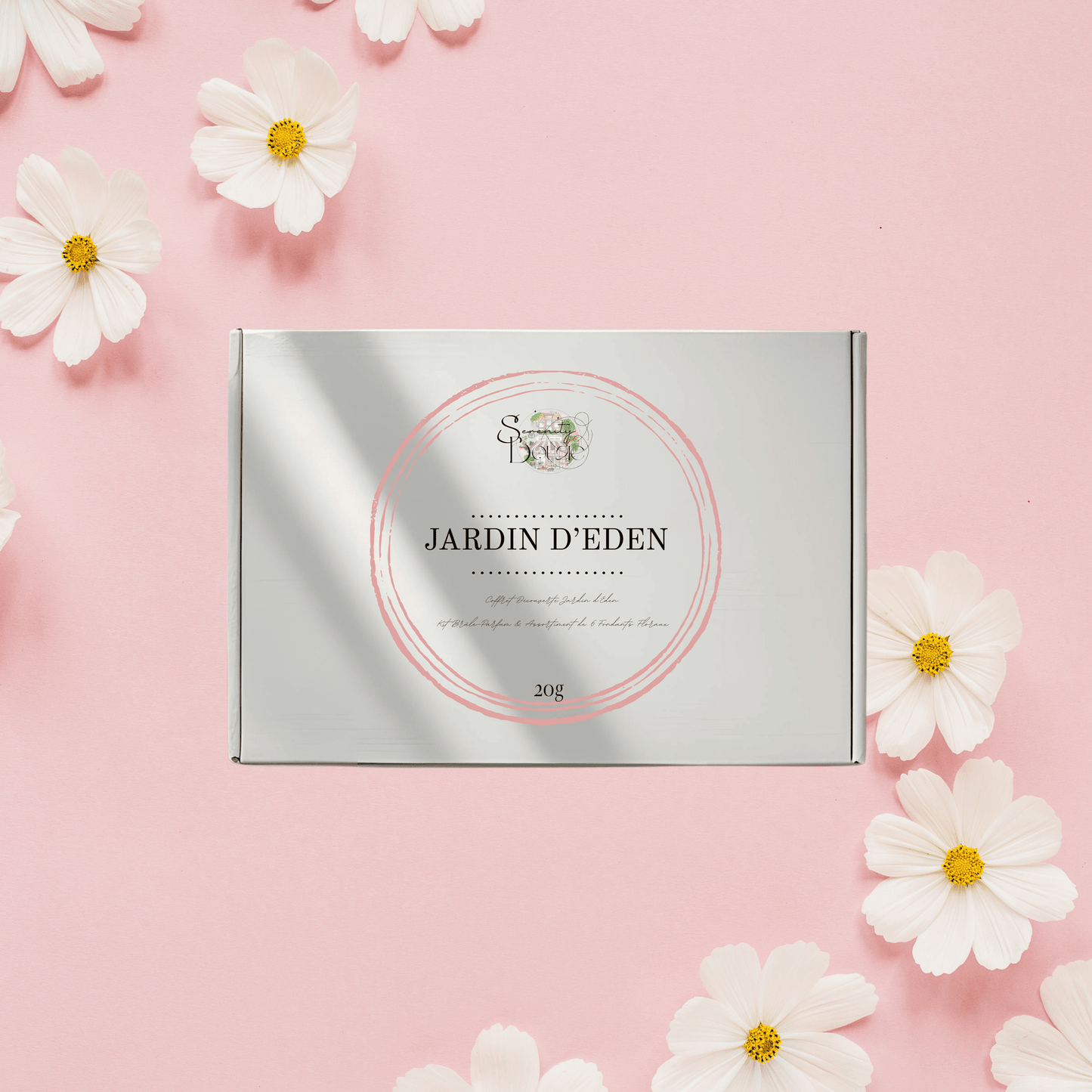 Coffret cadeau Fondants Parfumés fermé Jardin d'Éden. Boîte blanche et argentée sur fond rose avec fleurs blanches. Thème Floral, Kit Découverte.