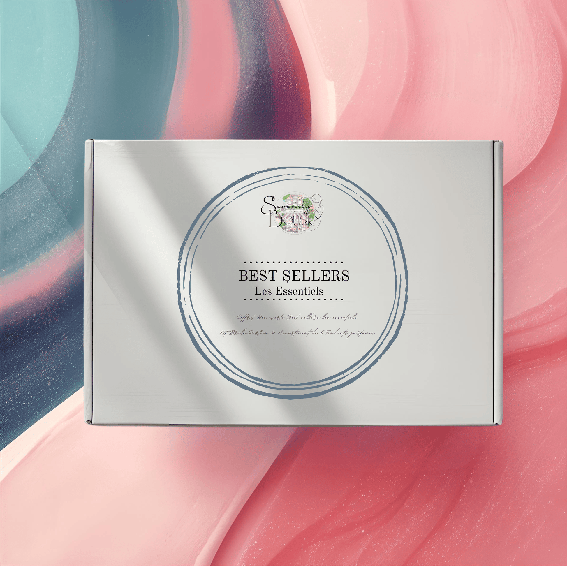 Coffret cadeau Fondants Parfumés "Best Sellers Les Essentiels" fermé, sur un fond abstrait rose et bleu. Kit découverte des parfums populaires.