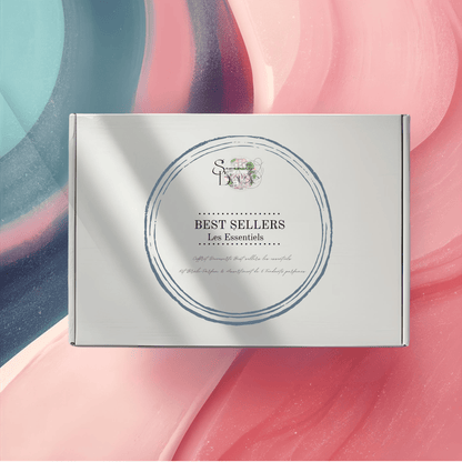 Coffret cadeau Fondants Parfumés "Best Sellers Les Essentiels" fermé, sur un fond abstrait rose et bleu. Kit découverte des parfums populaires.